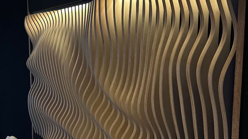 Verlichte golvende wand van gefreesde multiplex lamellen